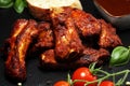 Spicy hot grilled spare ribs from a summer BBQ served with fresh tomatoes on an vintage cutting board Royalty Free Stock Photo