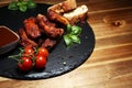 Spicy hot grilled spare ribs from a summer BBQ served with fresh tomatoes on an vintage cutting board Royalty Free Stock Photo