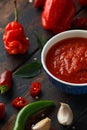 Spicy hot sweet chili sauce with mix of chilli pepper, garlic and tomatoes on rustic wooden background Royalty Free Stock Photo