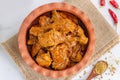 Spicy Indian Chicken Curry in a Clay Pot Garnished with Onion, Lemon and Cilantro Top Down Photo