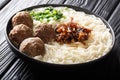 Spicy Indonesian bakso meatballs with noodles, caramelized onions, greens and broth close-up on a plate. horizontal
