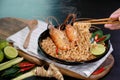 Spicy instant noodles soup and rivers shrimp with hand and chopsticks, on black table background. Tom Yum Kung name in Thailand Royalty Free Stock Photo