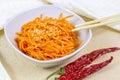 Spicy Korean carrot salad in a white bowl on light background.
