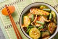 Spicy Korean cucumber salad in kimchi sauce with sesame seeds in a bowl with chopsticks. Horizontal top view Royalty Free Stock Photo