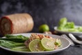 Spicy lime pork salad with kale, galangal, chilli and garlic in a white plate on a black cement floor Royalty Free Stock Photo