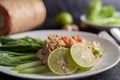 Spicy lime pork salad with kale, galangal, chilli and garlic in a white plate on a black cement floor Royalty Free Stock Photo