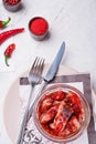 Spicy marinated herring  fillet in transporant bowl with red pepper, fresh chili  and seasonings. served at white table. top view Royalty Free Stock Photo