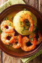 Spicy mofongo with plantains, garlic and chicharron served with shrimp and broth close-up on the table. Vertical top view