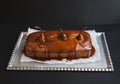 Spicy pear cake with caramel topping on a silver dish on dark