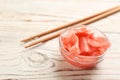 Spicy pickled ginger and chopsticks on white wooden table, closeup. Space for text Royalty Free Stock Photo