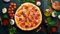 Spicy pizza with sausages and chili peppers. On a black stone background. Royalty Free Stock Photo