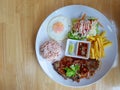 Spicy pork steak garnished with salad, French fried, fried egg, and brown rice