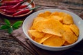 Spicy potato chips in white bowl and chili on wooden plate Royalty Free Stock Photo