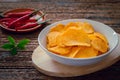 Spicy potato chips in white bowl and chili on wooden plate Royalty Free Stock Photo