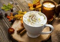 Spicy pumpkin latte with whipped cream. Autumn coffee cup with pumpkin and cinnamon spice on wooden table with fall candle and Royalty Free Stock Photo