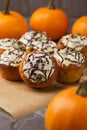 Spicy pumpkin muffins decorated ghosts, spiderweb for Halloween celebration. Autumn composition with pumpkins, cupcakes on dark