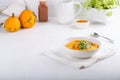 Spicy pumpkin soup served with pumpkin seeds and parsley.  Bowl with autumn squash soup on white table Royalty Free Stock Photo