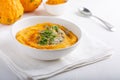 Spicy pumpkin soup served with pumpkin seeds and parsley.  Bowl with autumn squash soup on white table Royalty Free Stock Photo