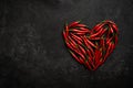 Spicy red chili pepper in the shape of a heart on a dark stone background Royalty Free Stock Photo