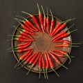 Spicy red peppers spread out in a circle on the clay flat dish.