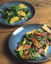 Spicy roast beef, mango and avocado salad served in a blue plate over rustic wooden background Royalty Free Stock Photo