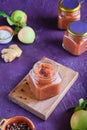 Spicy sauce, apple chutney in a glass jar on a wooden board on a purple concrete background. Indian food Royalty Free Stock Photo