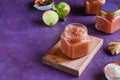 Spicy sauce, apple chutney in a glass jar on a wooden board on a purple concrete background. Indian food Royalty Free Stock Photo