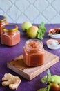 Spicy sauce, apple chutney in a glass jar on a wooden board on a purple concrete background. Indian food Royalty Free Stock Photo