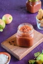 Spicy sauce, apple chutney in a glass jar on a wooden board on a purple concrete background. Indian food Royalty Free Stock Photo