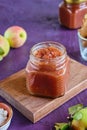 Spicy sauce, apple chutney in a glass jar on a wooden board on a purple concrete background. Indian food Royalty Free Stock Photo