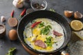 spicy scrambled eggs or omlette in a frying pan with bacon, garlic and pepper, ingredients around on the tables Royalty Free Stock Photo