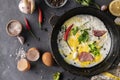 spicy scrambled eggs or omlette in a frying pan with bacon, garlic and pepper, ingredients around on the tables Royalty Free Stock Photo