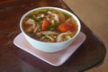 Spicy soup with cartilage in a white plastic bowl on a pink plastic square plate, on wooden table, nature, food, vegetables Royalty Free Stock Photo