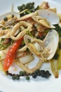 Spicy stir fried clam with squid and pepper cople slice finger root topping chili on plate