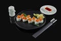 Spicy sushi rolls with rice, norms, mayonnaise, tobiko caviar and salmon on a black ceramic plate on a black background. Japanese Royalty Free Stock Photo