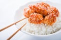 Spicy sweet and sour chicken with sesame and rice on white background close up