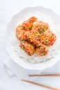 Spicy sweet and sour chicken with sesame and rice on white background top view