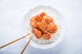 Spicy sweet and sour chicken with sesame and rice on white background top view