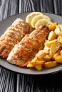 Spicy tasty grilled mackerel filet with potato wedges and lemon close-up on a plate. vertical Royalty Free Stock Photo
