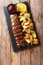 Spicy tenderloin pork in honey-garlic orange glaze with potato wedges close-up on a plate. Vertical top view Royalty Free Stock Photo