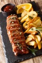 Spicy tenderloin pork in honey-garlic orange glaze with potato wedges close-up on a plate. vertical Royalty Free Stock Photo