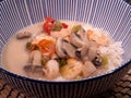 Spicy Thai coconut soup with shrimps, tomatoes, mushrooms and jasmine rice served in a large blue and white bowl