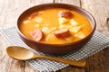 Spicy thick potato soup with sausages and sour cream close-up in a plate. horizontal