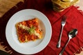 Spicy Tomato and Beef Lasagna served in plate with fork and spoon isolated on red napkin top view of fast food on table Royalty Free Stock Photo