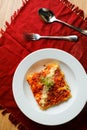 Spicy Tomato and Beef Lasagna served in plate with fork and spoon isolated on red napkin top view of fast food on table Royalty Free Stock Photo