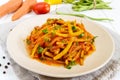 Spicy warm salad of green beans in tomato sauce on a plate on a white wooden background Royalty Free Stock Photo