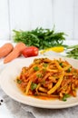 Spicy warm salad of green beans in tomato sauce on a plate on a white wooden background. Royalty Free Stock Photo