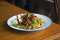 Spicy Winged bean salad with shrimp and boiled egg in white dish on wooden table. Thai food call