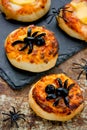 Spider pizza on Halloween. Homemade mini pizza decorated with olives in the form of a spider for kids treats