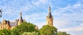 Spiers of Schwerin Castle behind green tree tops against a blue sky with white clouds